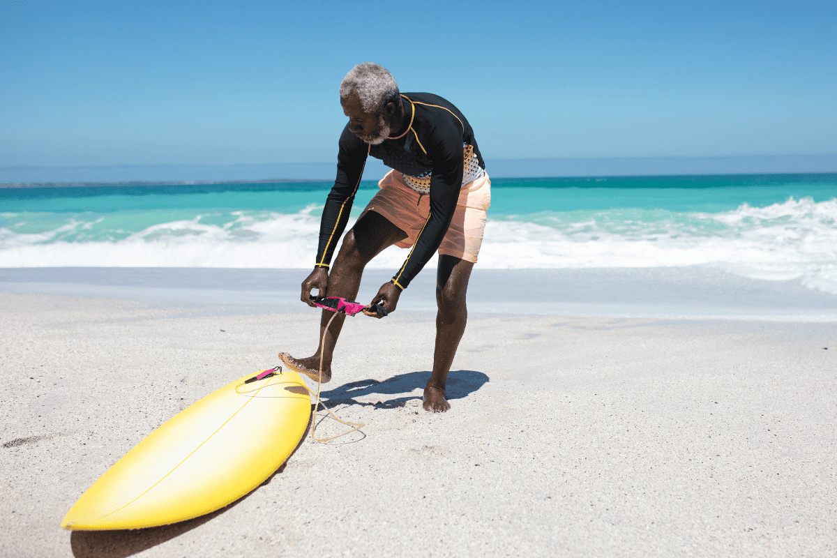 Senior man with surfboard on beach
